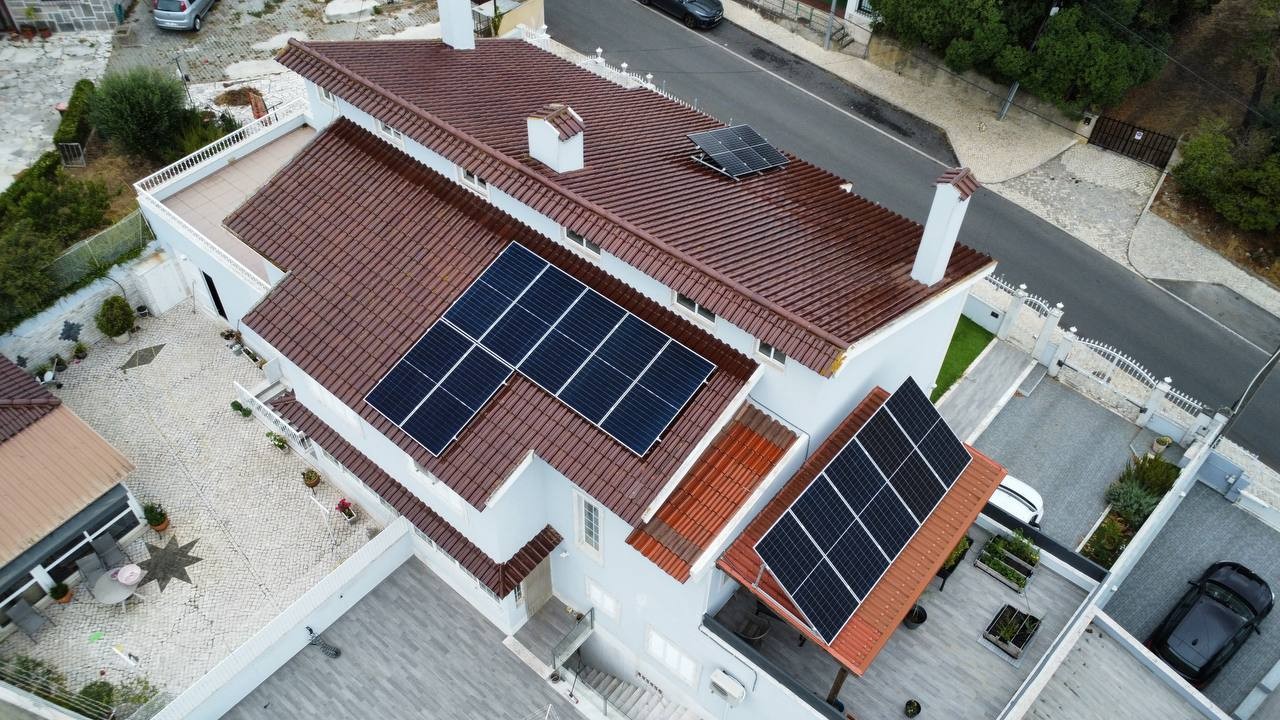 Vista aérea de uma moradia em Sintra com telhado de telha e painéis solares instalados em duas águas
